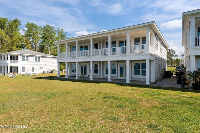 back of property with a yard and a balcony