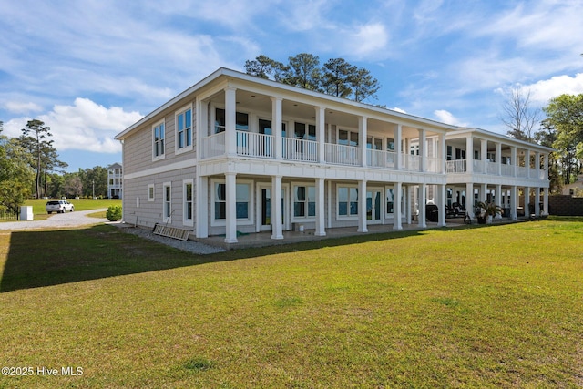 back of house featuring a lawn and a balcony
