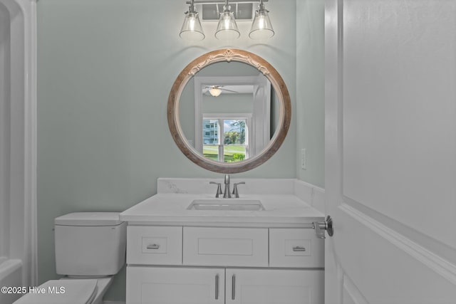 half bathroom with vanity, ceiling fan, and toilet