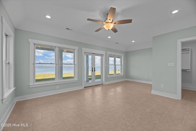 empty room featuring visible vents, baseboards, a water view, french doors, and a ceiling fan
