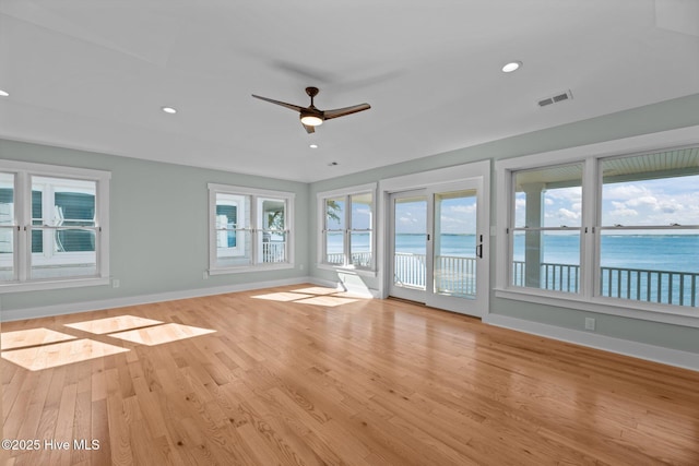 interior space with ceiling fan, visible vents, baseboards, light wood finished floors, and a water view