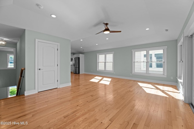 unfurnished living room featuring baseboards, a ceiling fan, light wood-style flooring, and a wealth of natural light