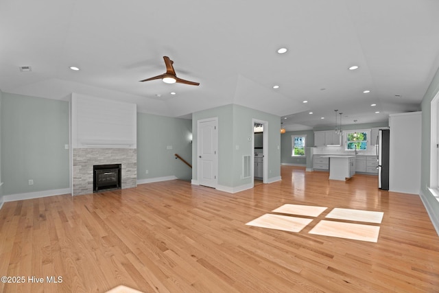 unfurnished living room with baseboards, a stone fireplace, ceiling fan, recessed lighting, and light wood-style flooring