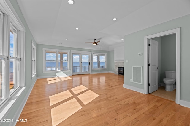 unfurnished living room featuring visible vents, a ceiling fan, light wood-style floors, and a fireplace