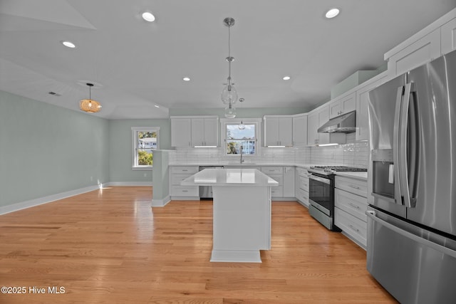 kitchen featuring a sink, stainless steel appliances, tasteful backsplash, under cabinet range hood, and a kitchen island