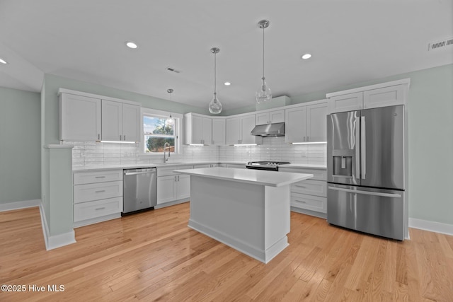 kitchen featuring visible vents, light countertops, under cabinet range hood, a sink, and stainless steel appliances
