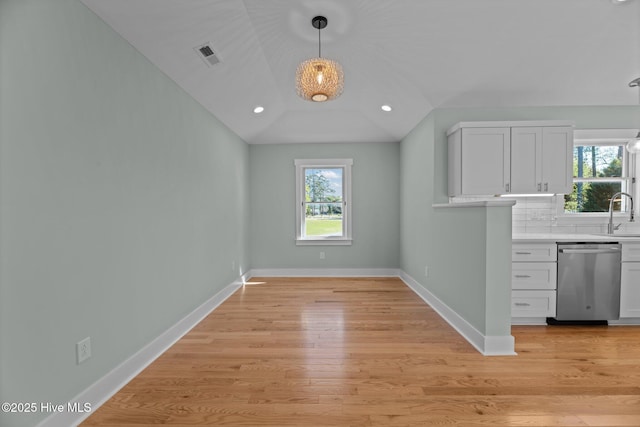 unfurnished dining area featuring a sink, plenty of natural light, light wood-style floors, and visible vents