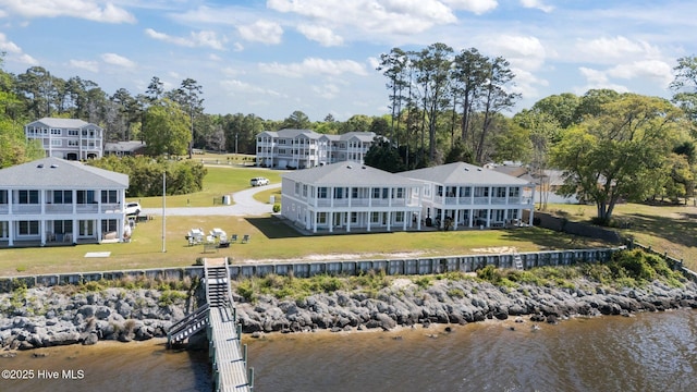 back of house featuring a lawn, a water view, and stairs