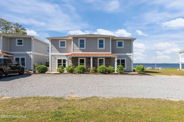 view of front of house featuring a standing seam roof, a water view, and a front lawn