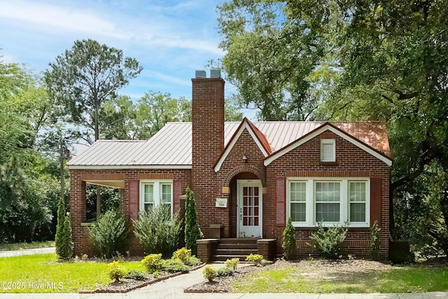 503 Spring St, Hamlet, NC 28345 - tudor home with brick siding, a chimney, cooling unit, and metal roof