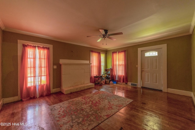 503 Spring St, Hamlet, NC 28345 - entrance foyer with crown molding, a ceiling fan, a fireplace with raised hearth, wood finished floors, and baseboards
