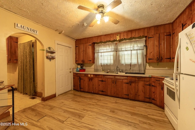 503 Spring St, Hamlet, NC 28345 - kitchen with a sink, white appliances, brown cabinetry, arched walkways, and ceiling fan