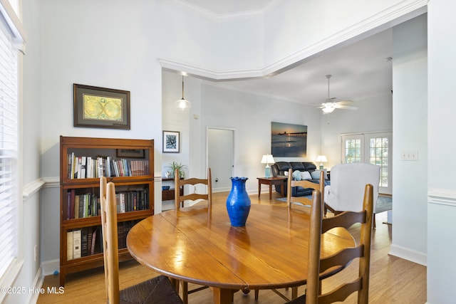 dining room with crown molding, a ceiling fan, baseboards, and light wood-type flooring