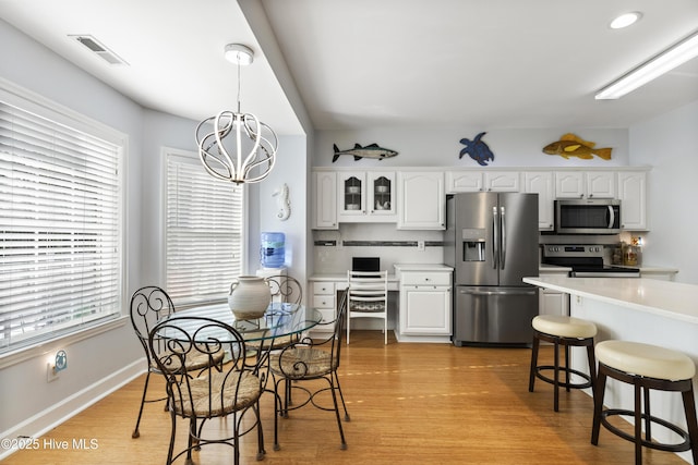 kitchen featuring stainless steel appliances, visible vents, white cabinetry, and a wealth of natural light