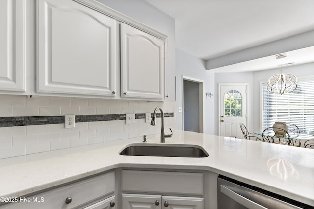 kitchen featuring a sink, dishwasher, a chandelier, white cabinetry, and tasteful backsplash