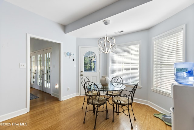 dining room with baseboards, a notable chandelier, visible vents, and wood finished floors