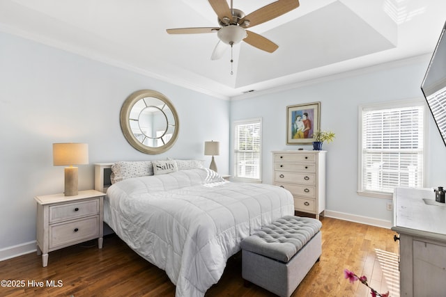 bedroom with visible vents, wood finished floors, baseboards, a raised ceiling, and ornamental molding