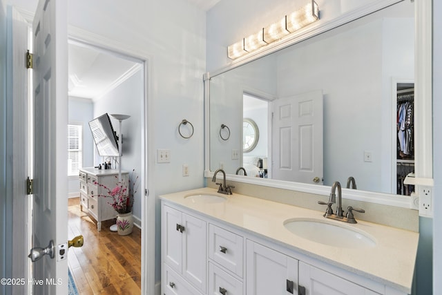 full bath with crown molding, double vanity, a sink, and wood finished floors