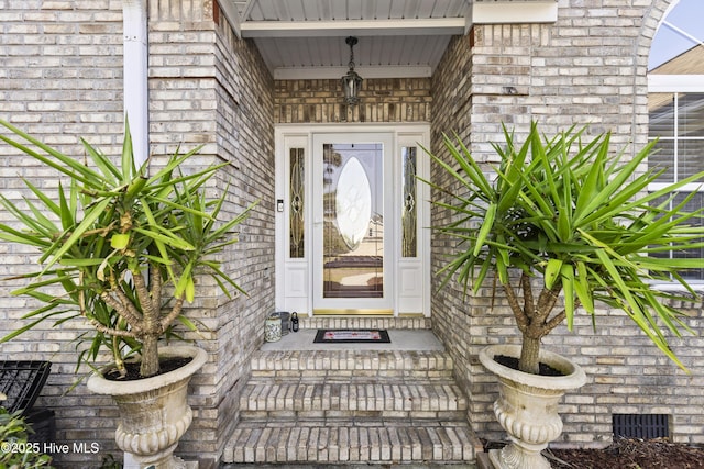 view of exterior entry with brick siding and visible vents