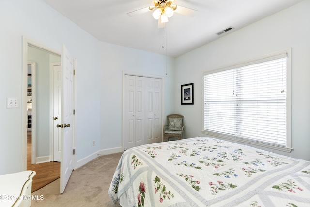 bedroom with ceiling fan, light colored carpet, visible vents, baseboards, and a closet