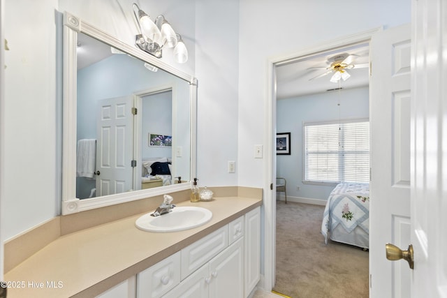 ensuite bathroom with connected bathroom, a ceiling fan, baseboards, and vanity