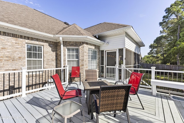 wooden terrace featuring a sunroom and fence