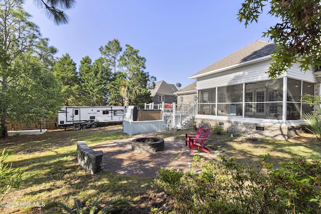 view of yard featuring a patio, a sunroom, and an outdoor fire pit