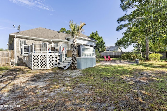 rear view of property with brick siding, a wooden deck, a fenced backyard, and roof with shingles