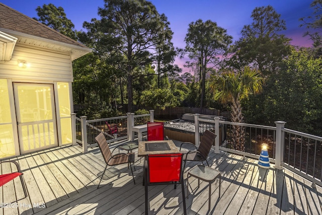 deck at dusk with a fire pit and a fenced backyard