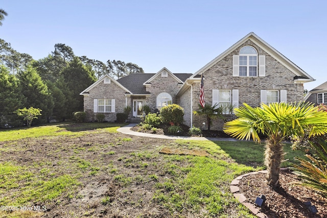 traditional-style house featuring a front yard and brick siding