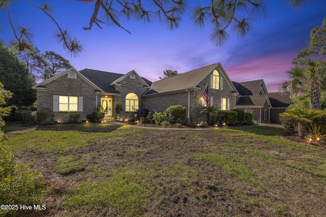 view of front of property featuring a lawn and brick siding