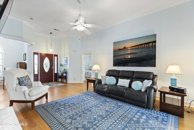 living area featuring baseboards, ornamental molding, a ceiling fan, and wood finished floors