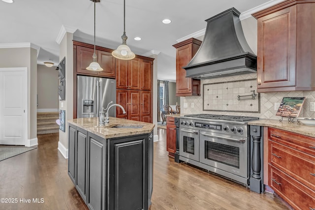 kitchen featuring appliances with stainless steel finishes, light stone countertops, a sink, custom exhaust hood, and ornamental molding