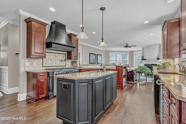 kitchen featuring ceiling fan, recessed lighting, custom range hood, a sink, and stainless steel range