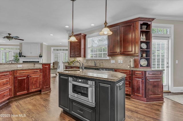 kitchen featuring a sink, decorative backsplash, ceiling fan, and dark wood-style floors