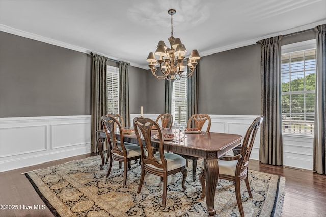 dining space featuring wainscoting, an inviting chandelier, ornamental molding, and wood finished floors
