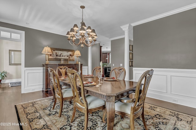 dining room featuring an inviting chandelier, wainscoting, a decorative wall, wood finished floors, and ornamental molding