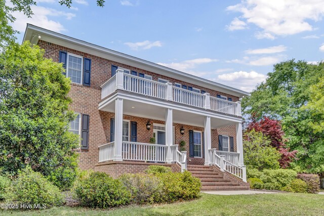 view of front of property with a porch, brick siding, and a balcony