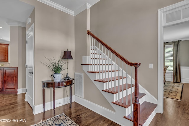 staircase featuring visible vents, ornamental molding, baseboards, and wood finished floors