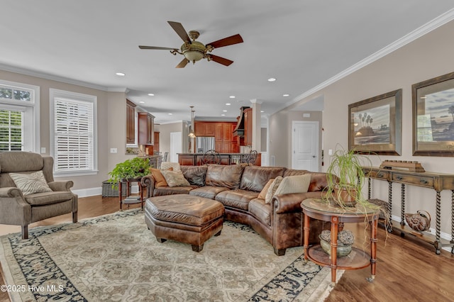 living area with a ceiling fan, baseboards, light wood-style floors, ornamental molding, and recessed lighting