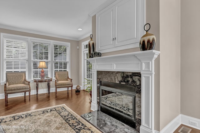 sitting room with visible vents, ornamental molding, baseboards, and wood finished floors