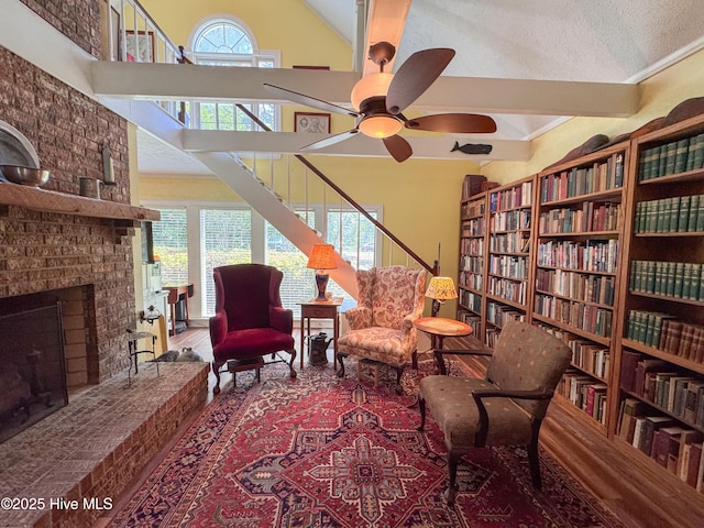 522 Hughes Rd, Hampstead, NC 28443 - living area with wall of books, a ceiling fan, a brick fireplace, high vaulted ceiling, and wood finished floors