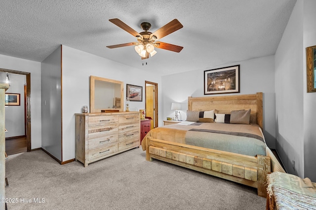 bedroom with light colored carpet, ceiling fan, baseboards, and a textured ceiling