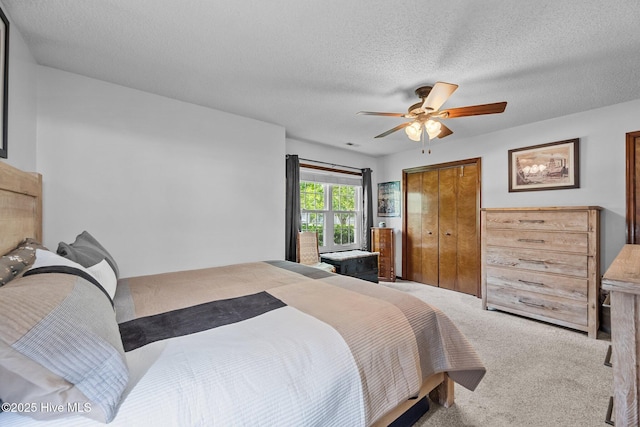 carpeted bedroom featuring a textured ceiling, ceiling fan, and a closet