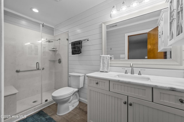 full bathroom featuring wood finished floors, a shower stall, toilet, and vanity