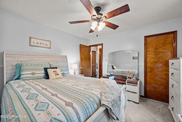bedroom with a textured ceiling, a ceiling fan, and light carpet