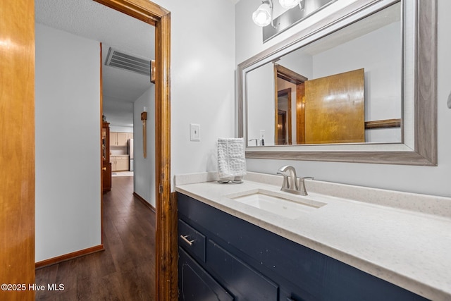 bathroom with baseboards, wood finished floors, and vanity