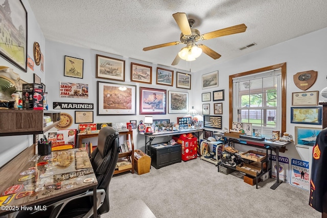 carpeted office featuring a textured ceiling, visible vents, and ceiling fan