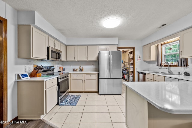 kitchen with stainless steel appliances, light countertops, a sink, visible vents, and a textured ceiling