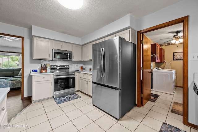 kitchen with a ceiling fan, a textured ceiling, stainless steel appliances, and washer / clothes dryer